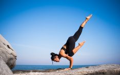 woman in yoga pose near ocean