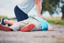 woman giving a man CPR on a rural road.